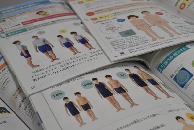 小学校3、4年を対象に使用されている現行の保健体育教科書。男女の発達の違いを写真やイラストで示している＝東京都千代田区で2025年11月4日午前11時53分、西本紗保美撮影