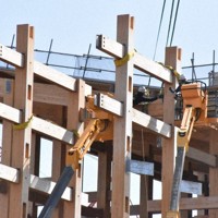 作業員が人の手でクレーンの先と大屋根リングの木材をつなげていた＝大阪市此花区で、長沼辰哉撮影