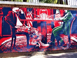 イランとの交渉の席に着いた米側代表（左）の姿が上着はスーツ、ズボンは軍服という壁画。軍事力で相手を威圧する米国の姿を風刺しているとみられる＝テヘランの旧米国大使館前で2021年6月16日、真野森作撮影
