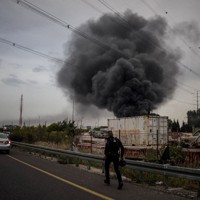 イランのミサイル攻撃による着弾現場に駆け付ける警察官＝イスラエル中部で3月13日、ロイター
