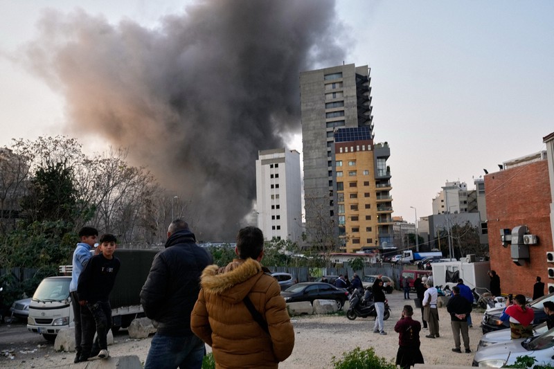 イスラエル軍の空爆で煙が上がる様子を見つめる住民たち＝ベイルートで2026年3月12日、AP
