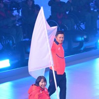 ミラノ・コルティナ冬季パラリンピックの閉会式、日の丸とともに入場した旗手の小川亜希（手前）と、小須田潤太＝コルティナ・カーリング五輪競技場で2026年3月15日午後9時1分、渡部直樹撮影