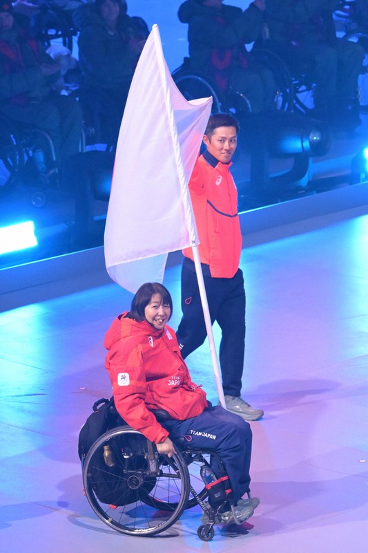 ミラノ・コルティナ冬季パラリンピックの閉会式、日の丸とともに入場した旗手の小川亜希（手前）と、小須田潤太＝コルティナ・カーリング五輪競技場で2026年3月15日午後9時1分、渡部直樹撮影