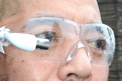 透明ゴーグルに装着した「ガイドワン」。先端の内側に極小ディスプレーがある。普段使う眼鏡にも装着できる＝島根県出雲市役所で、村瀬達男撮影