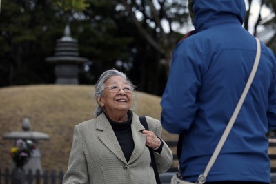 原爆供養塔前で知り合った外国人観光客と談笑する近藤紘子さん（左）＝広島市中区の平和記念公園で2026年3月3日、佐藤賢二郎撮影
