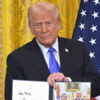 米ホワイトハウスで開かれた日米首脳会談後の共同記者会見で、石破茂首相に贈るメッセージ入りの記念写真を紹介するトランプ米大統領＝ワシントンで2025年2月7日、秋山信一撮影