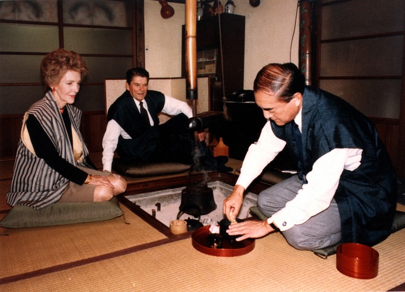 いろりのわきでお茶を立てる中曽根首相を見るレーガン大統領夫妻＝日の出山荘「青雲堂」で　1983年11月11日（代表撮影）
