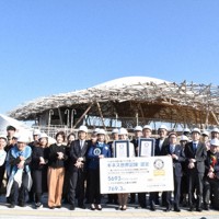 ギネス世界記録を達成したクラゲ館の前で記念撮影する関係者ら＝大阪市此花区で2026年3月16日、面川美栄撮影