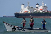 Fishermen pass an oil tanker in the Gulf of Venezuela off the shore of Punta Cardon, Venezuela, Jan. 14, 2026. (AP Photo/Matias Delacroix, FIle)