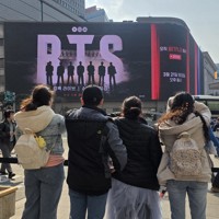 BTSのコンサートの告知画像が映し出されたデジタルサイネージの前に集まるファンら＝ソウルで2026年3月20日午後3時4分、日下部元美撮影