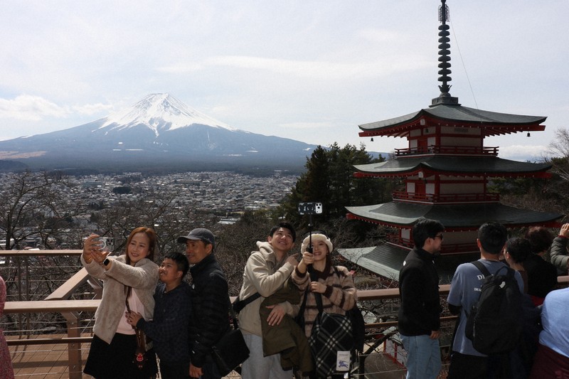展望デッキで写真撮影する外国人観光客ら。この日は国内の観光客も目立った＝山梨県富士吉田市の新倉山浅間公園で2026年3月18日午後0時23分、野田樹撮影