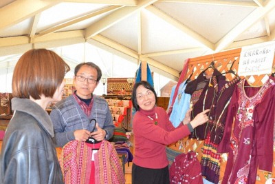 アジアの民族衣装を来場者に説明する「コミュニティパートナーズ」の束村康文・事務局長（左から2人目）と妻由里さん（同3人目）＝島根県邑南町の「道の駅邑南の里」で、村瀬達男撮影