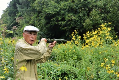 猟銃所持の許可を取り消されるきっかけとなった現場で射撃を再現する池上治男さん。当時は茂みが開けていた＝北海道砂川市で2025年8月20日午後4時45分、後藤佳怜撮影