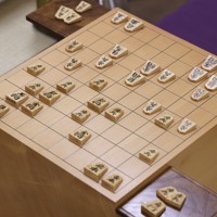 藤井聡太王将（右）に封じ手を見せる立会の桐山清澄九段（左）。中央は封じ手を指す永瀬拓矢九段＝大阪府高槻市の関西将棋会館で2026年3月26日午前8時58分、西村剛撮影