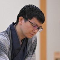 立会の桐山清澄九段（手前右）に封じ手を渡す挑戦者の永瀬拓矢九段（手前左）。奥右は藤井聡太王将＝大阪府高槻市の関西将棋会館で2026年3月25日午後6時8分、西村剛撮影