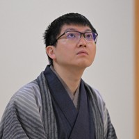 立会の桐山清澄九段（手前右）に封じ手を渡す挑戦者の永瀬拓矢九段（手前左）。奥右は藤井聡太王将＝大阪府高槻市の関西将棋会館で2026年3月25日午後6時8分、西村剛撮影