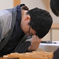 立会の桐山清澄九段（手前右）に封じ手を渡す挑戦者の永瀬拓矢九段（手前左）。奥右は藤井聡太王将＝大阪府高槻市の関西将棋会館で2026年3月25日午後6時8分、西村剛撮影