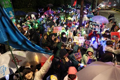 雨が降りしきる中、ペンライトなどを手に改憲やイラン攻撃に抗議するデモの参加者たち。多くの参加者が集まり、一部では歩道からあふれ出すほどだった＝国会前で2026年3月25日午後8時51分、後藤由耶撮影