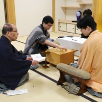 藤井聡太王将（右）に封じ手を見せる立会の桐山清澄九段（左）。中央は封じ手を指す永瀬拓矢九段＝大阪府高槻市の関西将棋会館で2026年3月26日午前8時58分、西村剛撮影