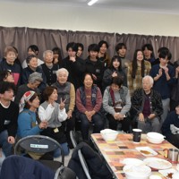 食事会の後、記念撮影するツアー参加者と能登高生、仮設住宅団地の高齢者ら＝石川県能登町で、2026年3月15日午後0時9分、中尾卓英撮影