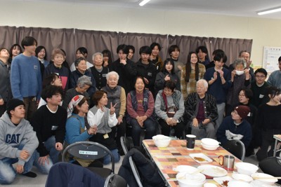 食事会の後、記念撮影するツアー参加者と能登高生、仮設住宅団地の高齢者ら＝石川県能登町で、2026年3月15日午後0時9分、中尾卓英撮影