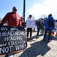 「我々は医療、住宅、教育を求めている。戦争ではない！」と書かれたプラカードを掲げる抗議デモの参加者＝米ワシントン近郊で2026年3月28日、松井聡撮影