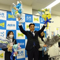 3選を決め、花束を掲げて喜ぶ石井登志郎氏（中央）＝西宮市内で2026年3月30日午前0時34分、山本真也撮影
