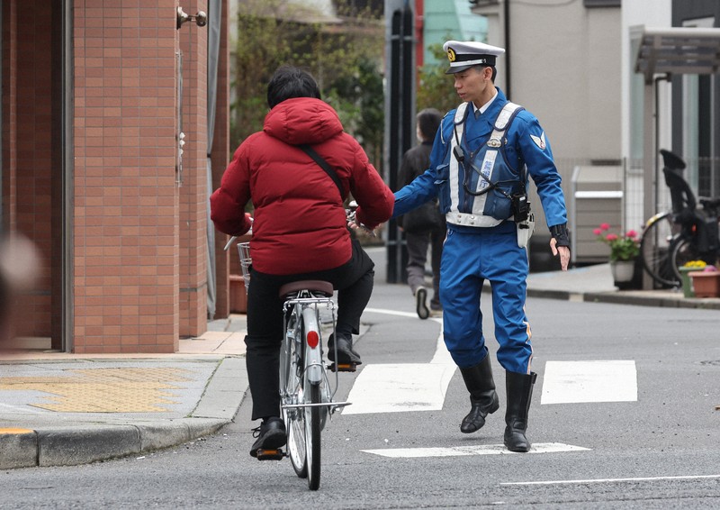 一時停止を守らずに道路を横断した自転車の利用者を取り締まりのために停車させる警察官＝東京都墨田区で2026年3月27日午前10時14分、後藤由耶撮影
