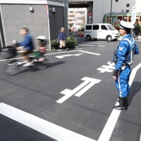 一時停止の標識を守るよう自転車の利用者に声をかける取り締まり中の警察官（右）＝東京都墨田区で2026年3月27日午前9時47分、後藤由耶撮影