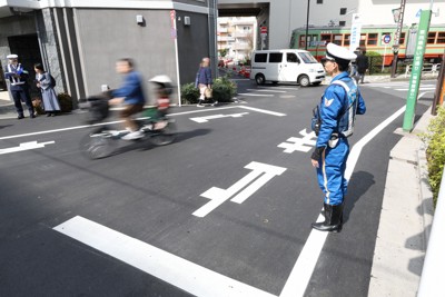 一時停止の標識を守るよう自転車の利用者に声をかける取り締まり中の警察官（右）＝東京都墨田区で2026年3月27日午前9時47分、後藤由耶撮影