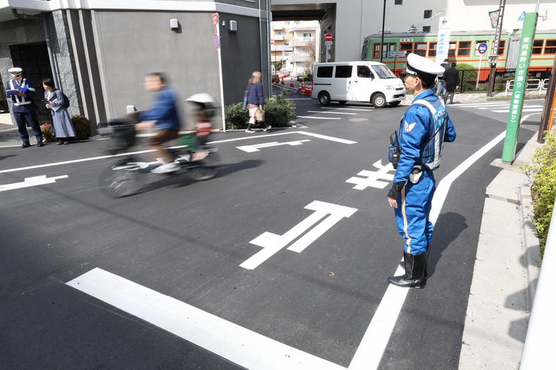 一時停止の標識を守るよう自転車の利用者に声をかける取り締まり中の警察官（右）＝東京都墨田区で2026年3月27日午前9時47分、後藤由耶撮影