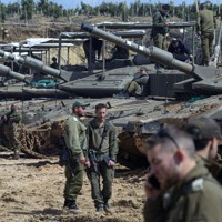 戦車の近くに立つイスラエル軍の兵士＝イスラエル北部のレバノンとの国境付近で2026年3月26日、ロイター