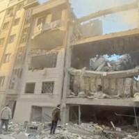 イランの首都テヘランで破壊された建物の前に立つ人々＝2026年4月1日公開の動画より（イラン赤新月社提供・ロイター）