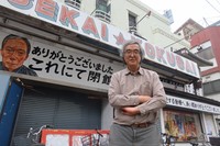 Manager Kazuhiko Tomioka poses in front of the Shinsekai Kokusai Gekijo theater on the day of its closing in Osaka's Naniwa Ward, March 31, 2026. The sign in the back features a portrait of Shoji Hachijo. (Mainichi/Yosuke Tsuyuki)
