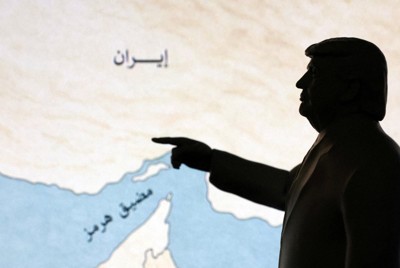ホルムズ海峡の地図を指さすトランプ米大統領を模したミニチュア＝2026年3月26日、ロイター