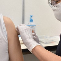ワクチンを接種する看護師（右）。医療現場では手袋が欠かせない＝さいたま市南区で2021年10月12日午後6時50分