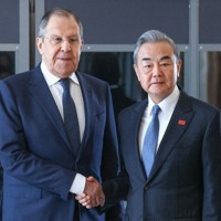 昨年2月、南アフリカ・ヨハネスブルクでの会談で握手する中国の王毅外相（右）とロシアのラブロフ外相（タス＝共同）