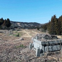 能登半島地震で被災した石川県輪島市の町野町金蔵地区。限界集落と呼ばれる地区内には、地震で倒壊したのか、台座だけの墓があった。奥にある田んぼは雑草が生い茂っている＝2026年3月11日、岩本一希撮影