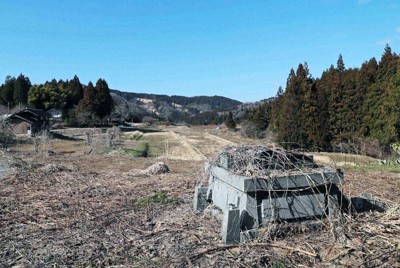 能登半島地震で被災した石川県輪島市の町野町金蔵地区。限界集落と呼ばれる地区内には、地震で倒壊したのか、台座だけの墓があった。奥にある田んぼは雑草が生い茂っている＝2026年3月11日、岩本一希撮影