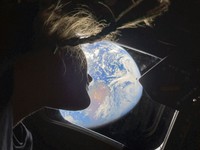 Artemis II mission specialist Christina Koch peers out of one of the Orion spacecraft's main cabin windows, looking back at Earth. (Kyodo)