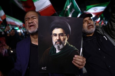 イランの最高指導者モジタバ・ハメネイ師のポスターを掲げる男性＝テヘランで2026年3月22日、WANAロイター
