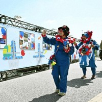 大阪・関西万博の開幕1周年を記念したイベントで、展示の写真を撮る人たち＝大阪メトロ夢洲駅前で、共同