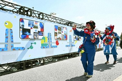 大阪・関西万博の開幕1周年を記念したイベントで、展示の写真を撮る人たち＝大阪メトロ夢洲駅前で、共同