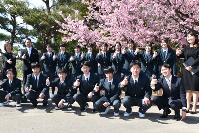 満開の桜の下で、親指で能登半島の形を作って記念撮影をする穴水高校の新入生と教職員ら＝いずれも石川県穴水町で、2026年4月8日午後2時16分、中尾卓英撮影