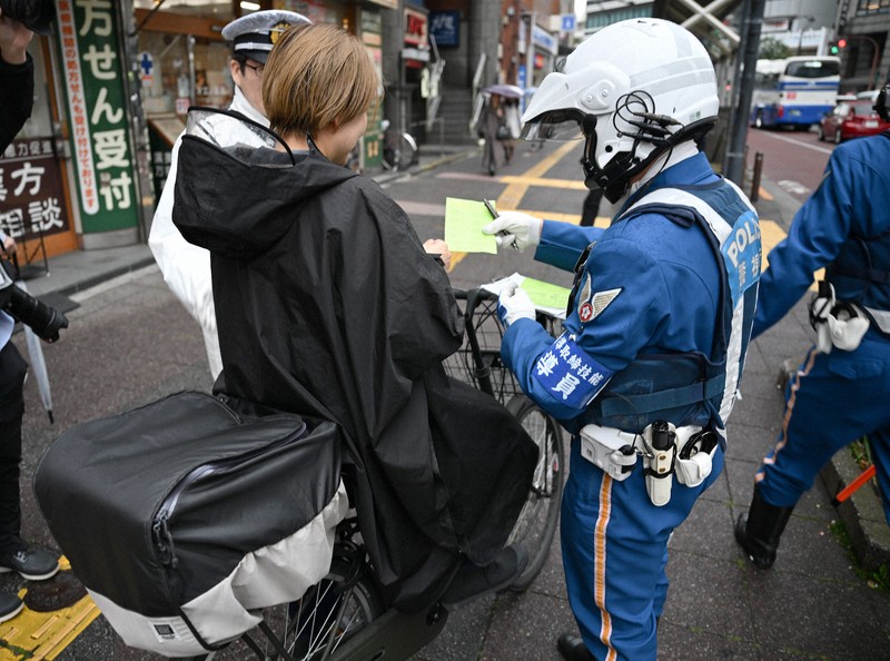 一時停止の標識に従わなかったため、警察官から警告を受ける自転車の運転手＝東京都北区で2026年4月1日午前9時17分、藤井達也撮影