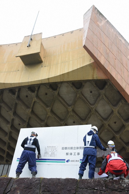 旧香川県立体育館の解体工事が始まり、敷地西側の道路前に看板を取り付ける作業員ら＝高松市福岡町で2026年4月10日午前8時43分、森田真潮撮影