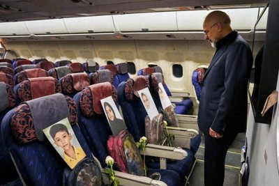 パキスタンの首都イスラマバードへ向かうとみられる機内で、子供たちの写真が並ぶ座席を見つめるイランのアラグチ外相＝ロイター