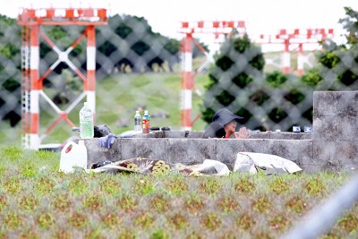 米軍普天間飛行場内で墓参りする人たち。奥には滑走路の誘導灯が立ち並んでいる＝沖縄県宜野湾市で2026年4月12日午後0時23分、喜屋武真之介撮影