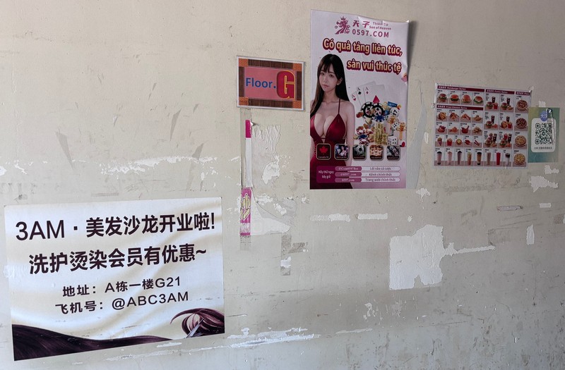 中国語で「ヘアサロンオープン！」と書かれたチラシなどが張られた壁＝タイ東北部スリン県近郊のカンボジアとの国境地帯で2026年4月7日、国本愛撮影