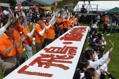 あすかルビーで「飛鳥・藤原の宮都」と書き、カメラに向かって手を振る参加者ら＝明日香村で、皆木成実撮影